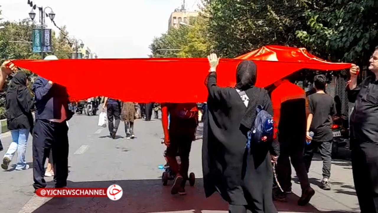 متبرک شدن زائران به پرچم حرم امام حسین (ع) در پیاده روی جاماندگان اربعین + فیلم
