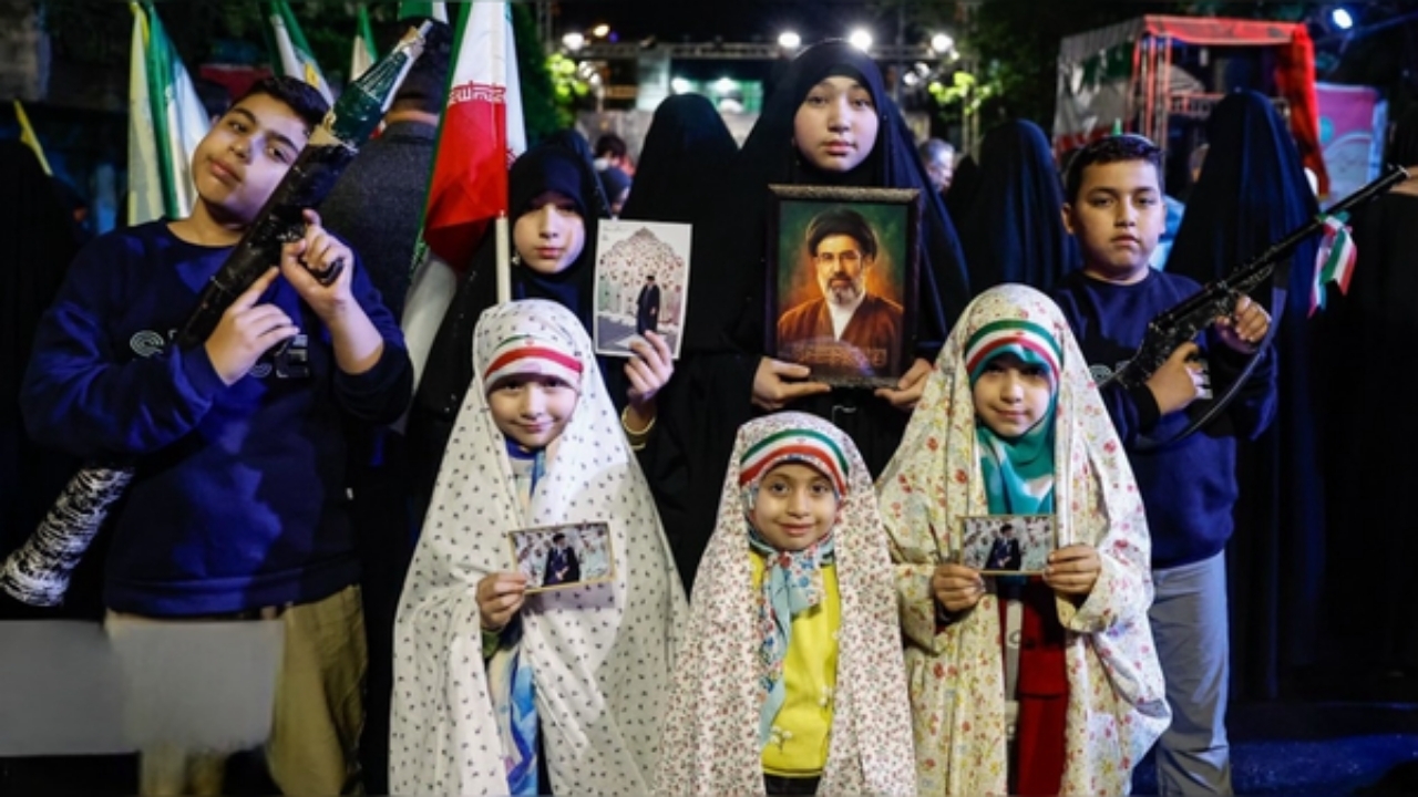 دخترکی که با عروسکِ هدیه رهبری زیر باران آرام  می‌گرفت