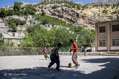 دانش آموزان مدرسه ی روستای ژیوار در حال بازی فوتبال در حیاط مدرسه میباشند