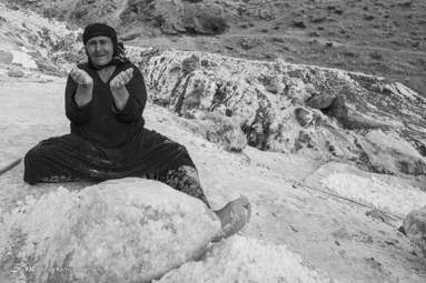 زن روستای  قلعه رشید در حال آسیاب کردن نمک با  سنگ های بزرگ 
