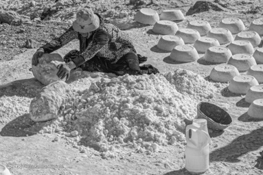 زن روستای  قلعه رشید در حال آسیاب کردن نمک با  سنگ های بزرگ 