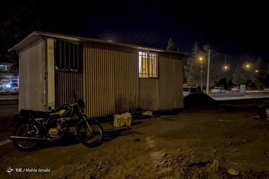 آقای آقاخانی 30ساله از آذربایجان غربی برای کار به کرمان آمده است و همزمان از دو ساختمان محافظت میکند، زندگی در کانکس نگهبانی که فاقد وسایل گرمایشی و آسایش است و دوری 6 ماهه از خانواده و دستمزد اندک